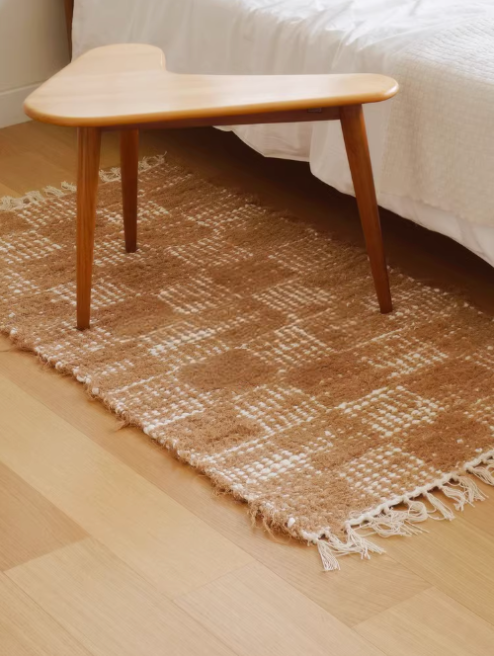 Handwoven cotton checkered rug (2.3x4.6) in natural tones, on wood floor by bedside.